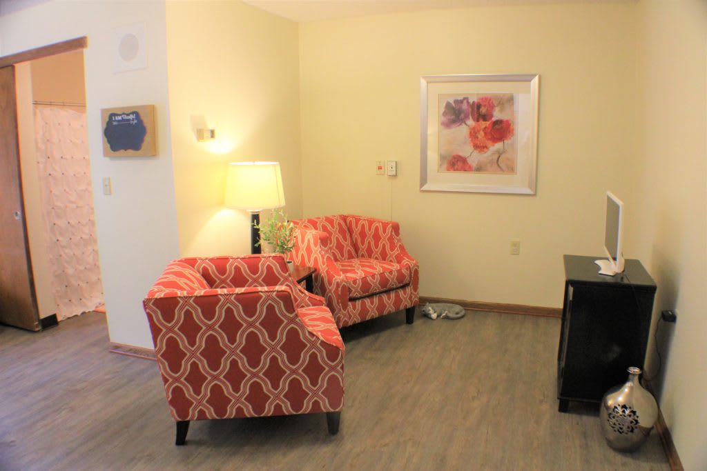 A cozy living room with patterned armchairs and a floor lamp.