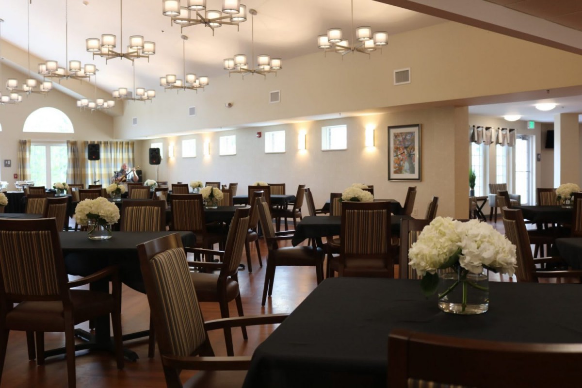 A spacious dining area with neatly arranged tables and chairs, featuring elegant floral centerpieces and ambient lighting.