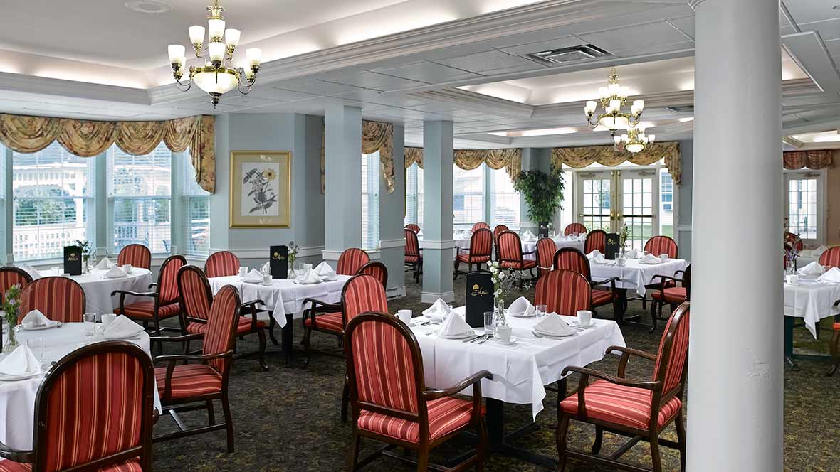 An elegant dining room with neatly arranged tables and chairs under chandeliers.