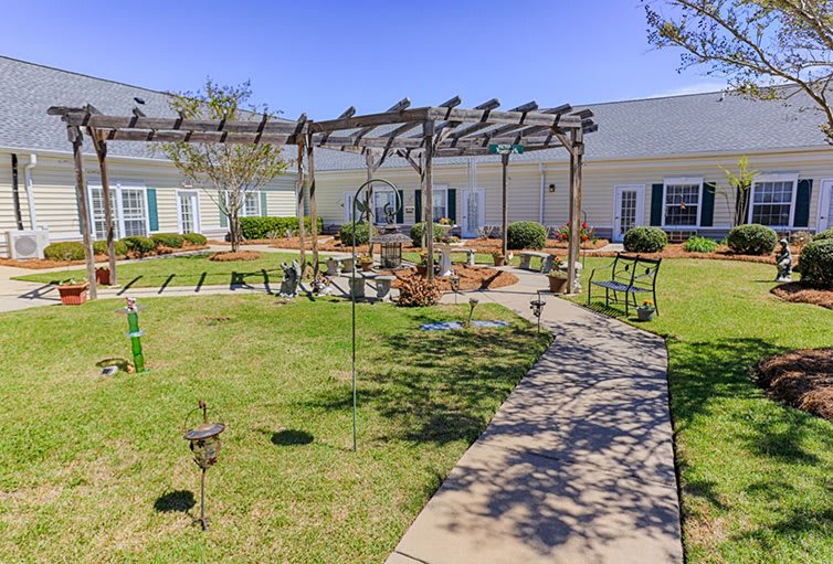 A serene garden with a pergola and pathway, surrounded by a well-maintained lawn.