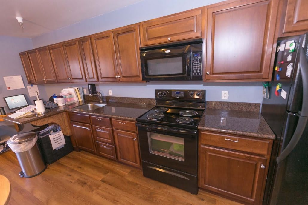 A modern kitchen with wooden cabinets, an oven, stove, and microwave set against a granite countertop.