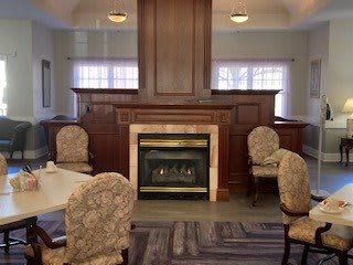 A cozy dining area with a central fireplace surrounded by upholstered chairs.