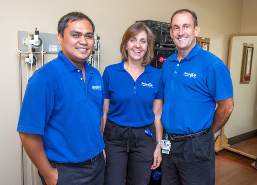 A professional team posing together in an office environment, all wearing matching blue shirts.