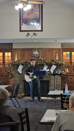 A guitarist performing live in a festive indoor setting, surrounded by holiday decorations.