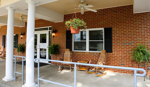 A cozy porch featuring rocking chairs and a hanging plant, perfect for relaxing outdoors.