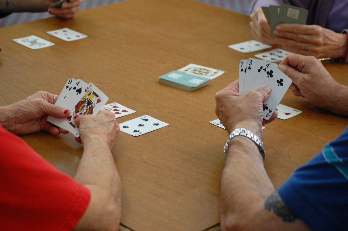 A group of people engaged in a card game around a table.