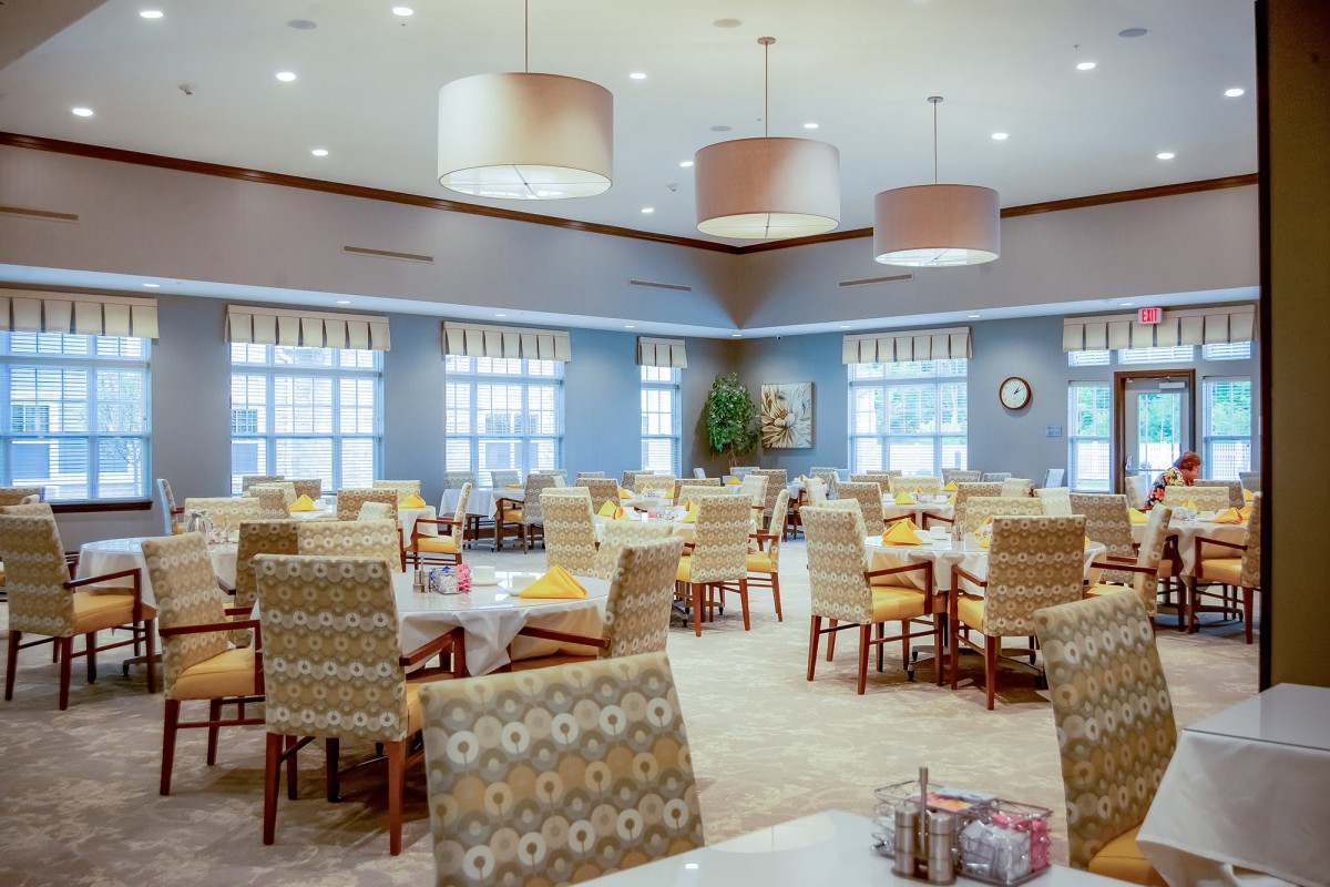 An elegant and spacious dining area with neatly arranged tables and chairs, illuminated by overhead lights.