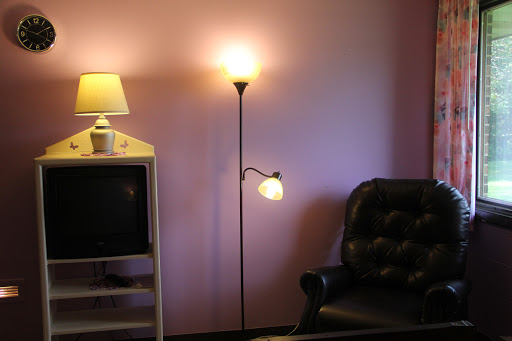 A cozy living room setup featuring a floor lamp, a side table lamp, a TV, and a comfortable sofa against a pink wall.