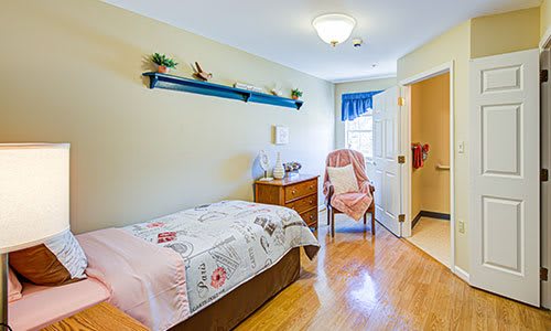A cozy bedroom with a single bed, chair, and dresser.