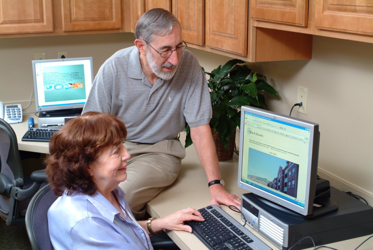 Two people working together on computers in an office setting.