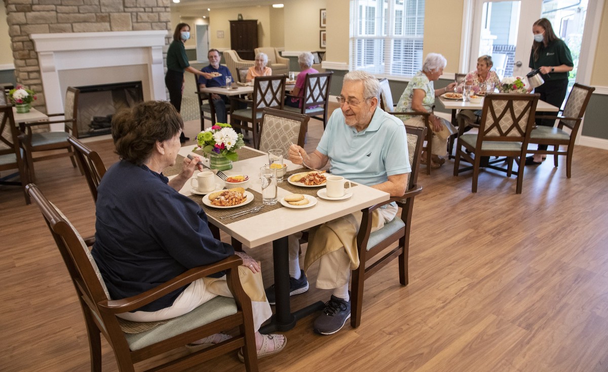 Elderly individuals enjoying a meal together in a communal dining area.