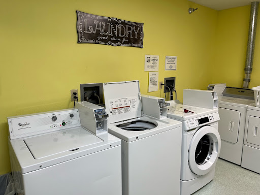 A bright laundry room featuring multiple washing machines.