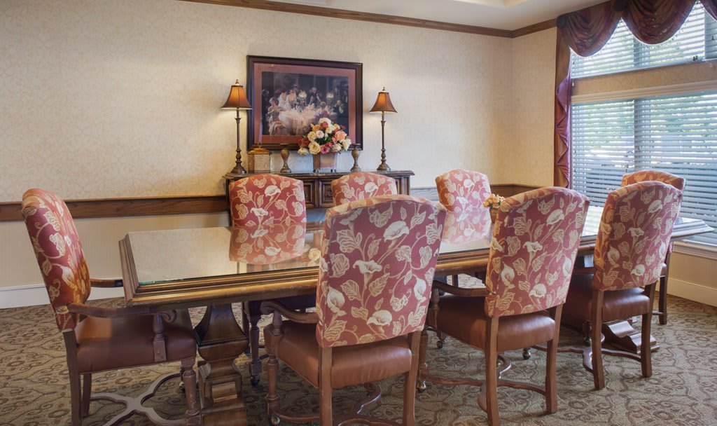 A cozy dining room with floral upholstered chairs and a decorative painting on the wall.