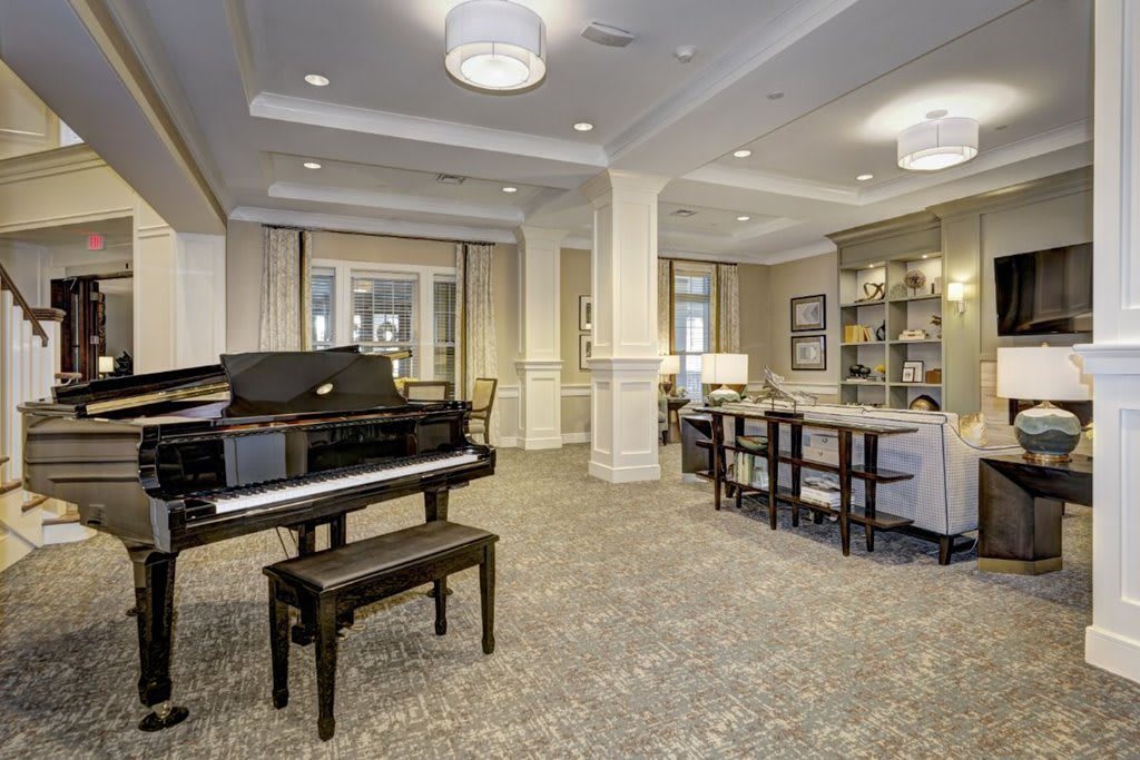 A spacious lobby with a grand piano, cozy seating area, and library shelves.