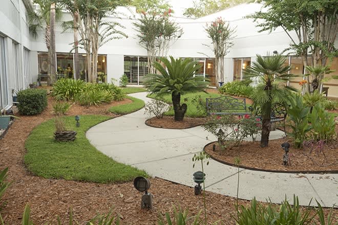 A beautifully landscaped garden with a winding pathway surrounded by lush greenery and adjacent to a building.
