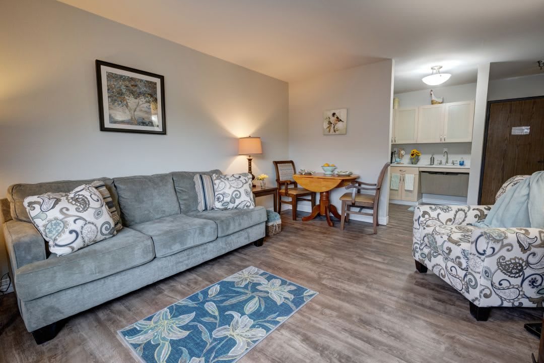 A cozy living room with a sofa, lamp, and dining area connected to the kitchen.