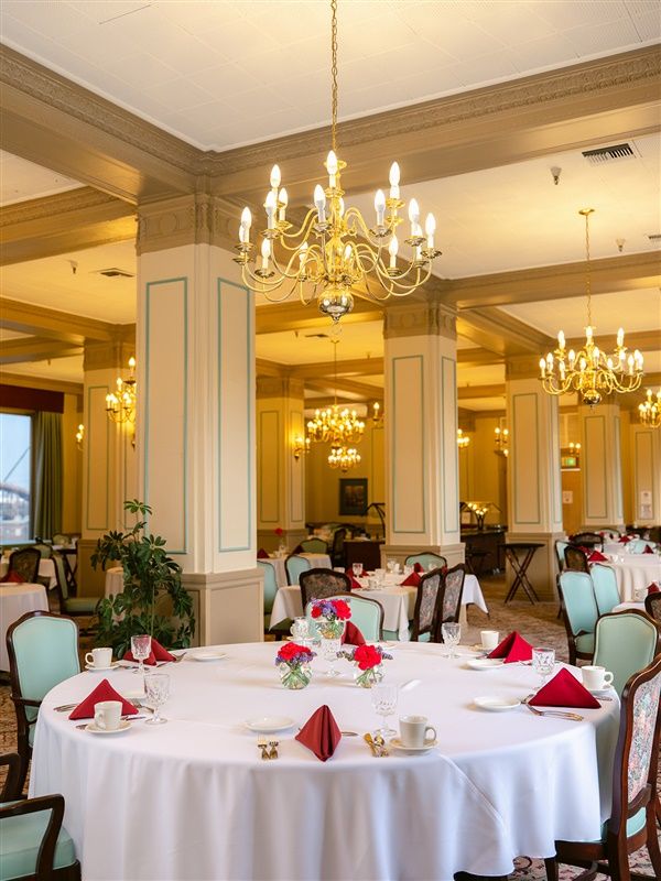 An elegant dining room with chandeliers and formally set tables.