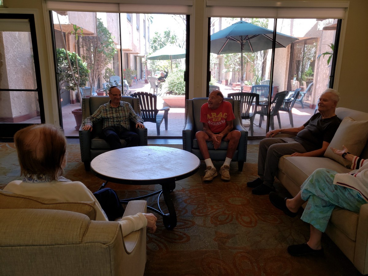 A group of seniors sitting in a circle indoors, engaged in conversation.