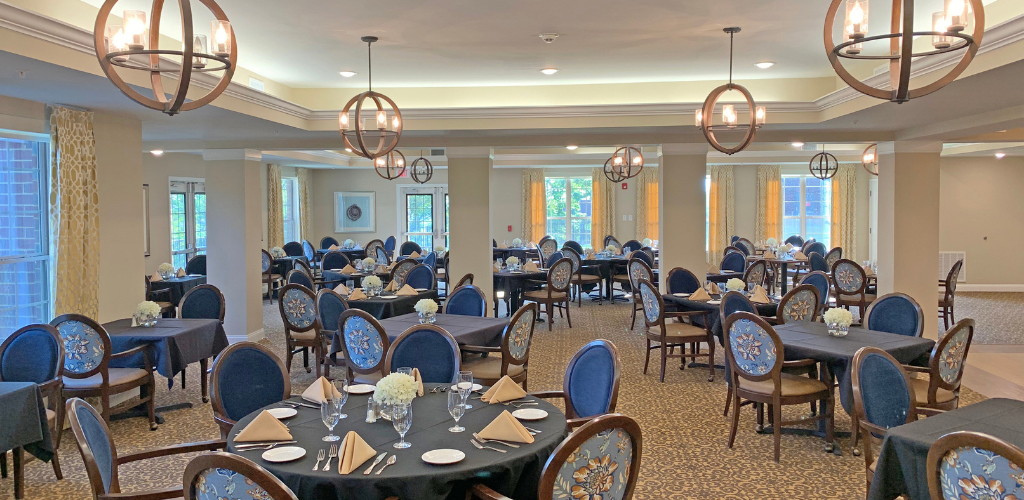 An elegant dining room with neatly arranged tables and chairs, set for a formal meal.