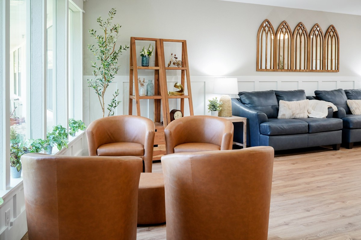 A cozy living room with brown chairs and a navy sofa, complemented by plants and decorative elements.