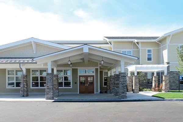 A modern building entrance with stone pillars and a peaked roof.