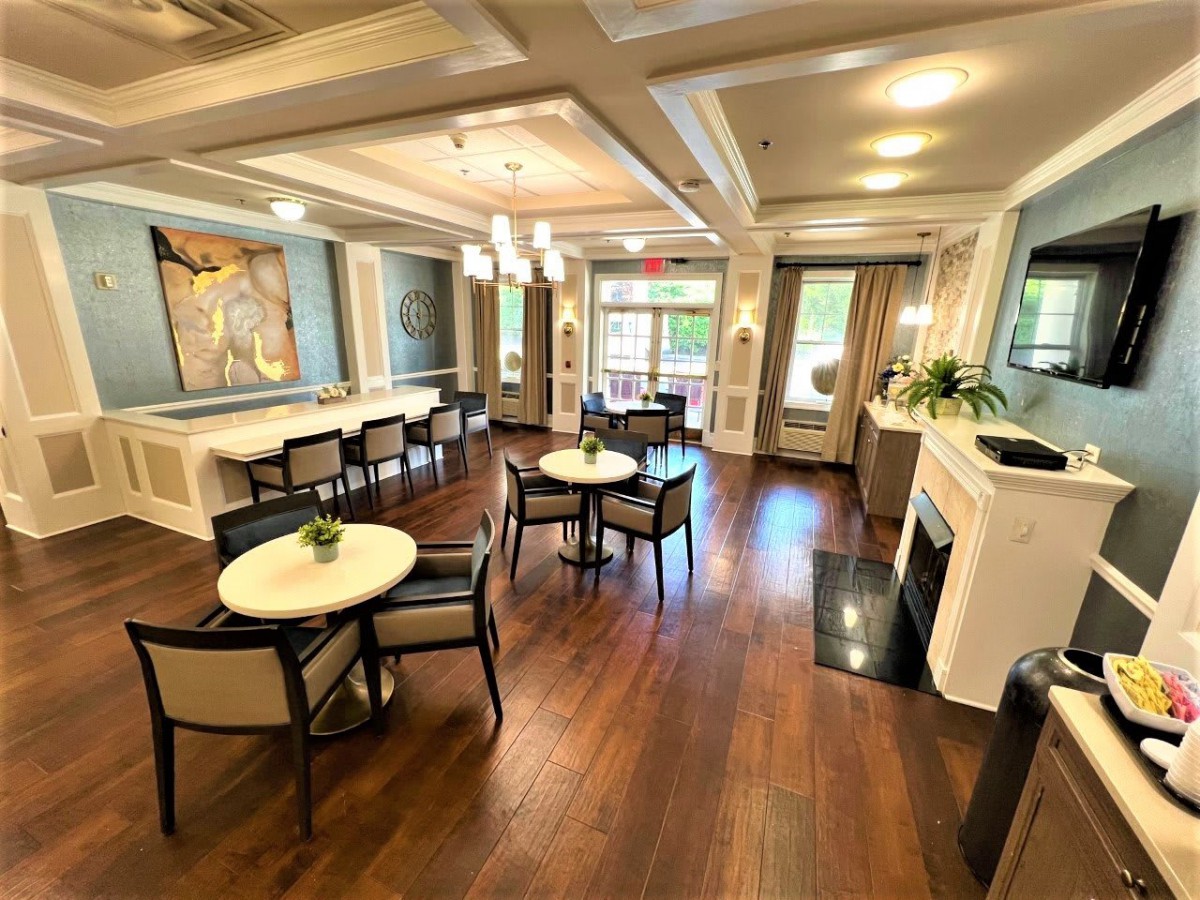 A well-decorated living area featuring tables, chairs, a fireplace, and artwork on the walls.
