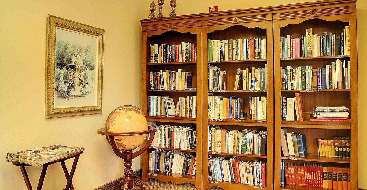 A cozy library corner with a wooden bookshelf filled with books and a decorative globe.