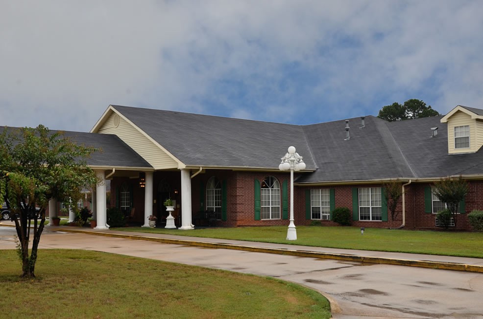 A single-story brick house with a neatly maintained yard and a driveway under a cloudy sky.