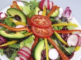 A vibrant and fresh vegetable salad with tomatoes, avocados, and radishes.
