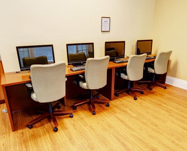 A row of computers with chairs in a workspace setting.