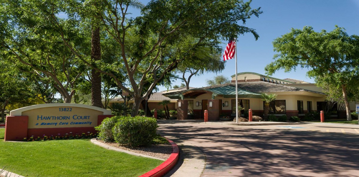 A landscaped driveway leading to a building with an American flag.