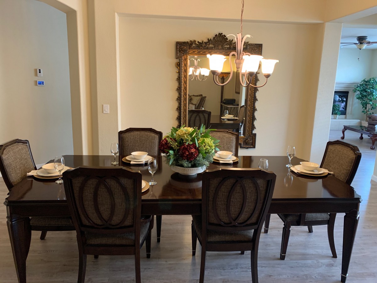 Elegant dining room with a dark wooden table set for a meal, complemented by a decorative mirror and chandelier.