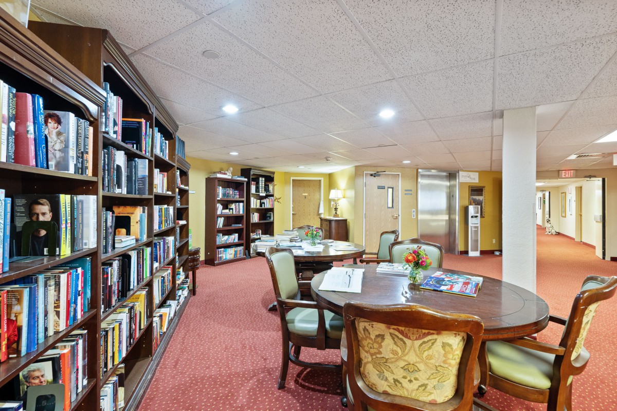 A cozy library with bookshelves and a reading area featuring a table and chairs.