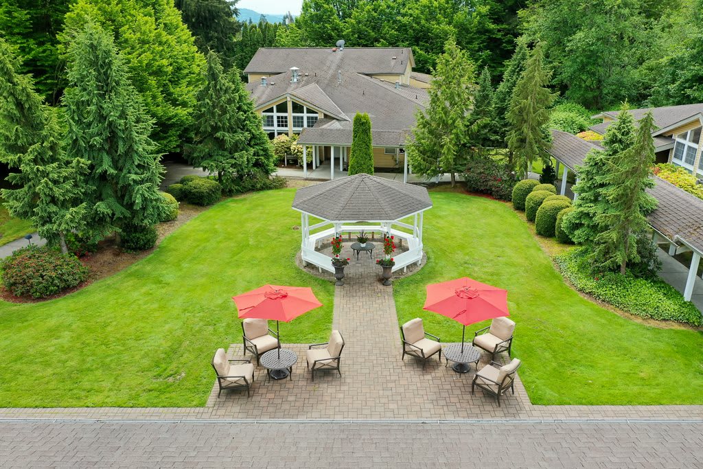 A beautiful house with a spacious garden, featuring a gazebo and outdoor seating with umbrellas.