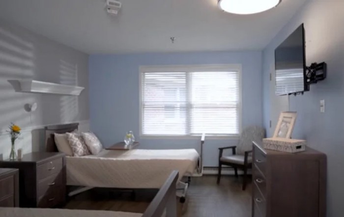 A hospital room featuring a bed, window, and seating area.