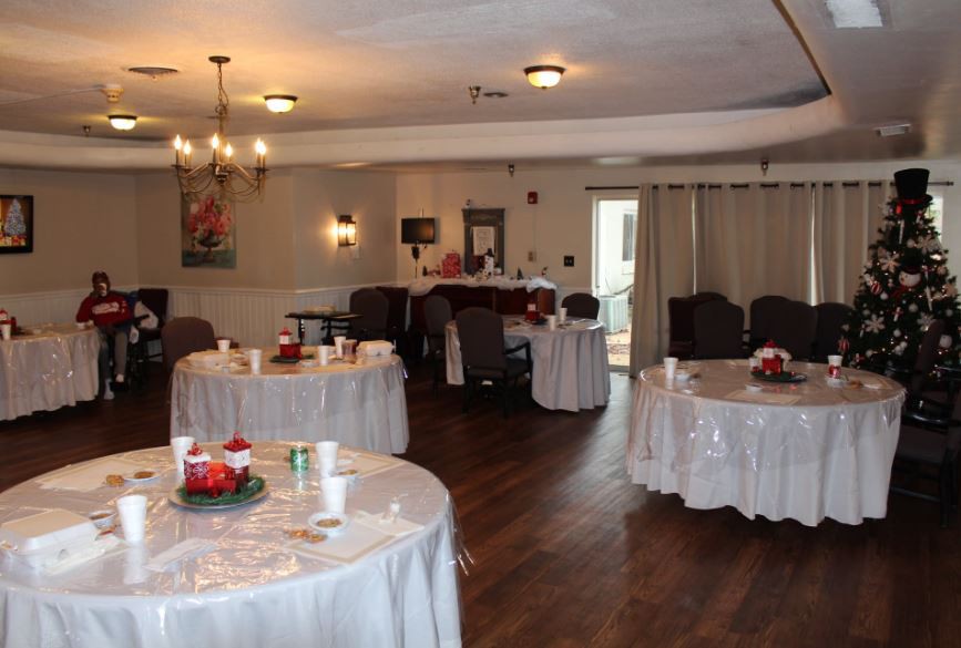 A decorated indoor banquet hall with round tables covered in white tablecloths.
