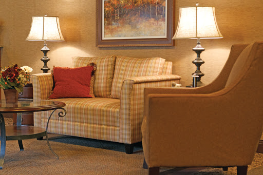 A cozy living room setting featuring a plaid sofa, an armchair, decorative lamps, and a stylish coffee table.