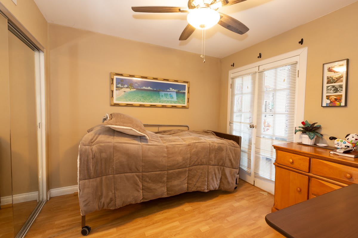 A cozy bedroom featuring a bed, ceiling fan, and French doors leading outside.
