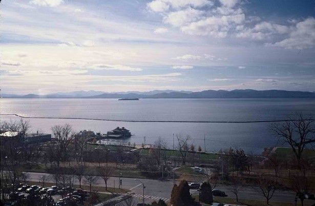 A scenic view of a lake with distant mountains under a cloudy sky.