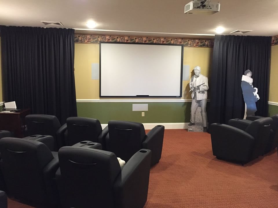 A cozy home theater setup with recliner chairs facing a large projection screen.