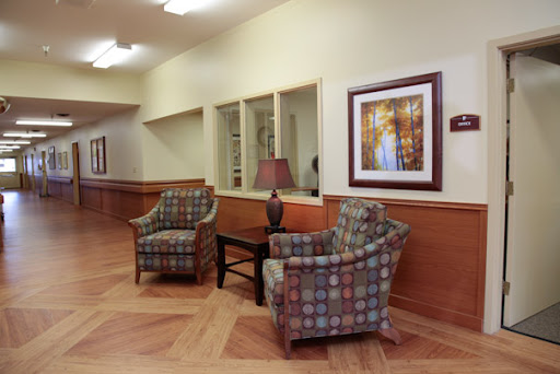 A cozy waiting area featuring two patterned chairs, a coffee table, and decorative artwork on the wall.