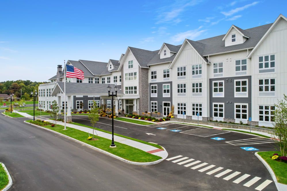A modern residential building with a front parking area and an American flag flying outside.