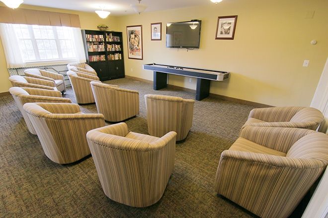 A cozy living room with multiple chairs arranged in front of a television and a bookshelf.