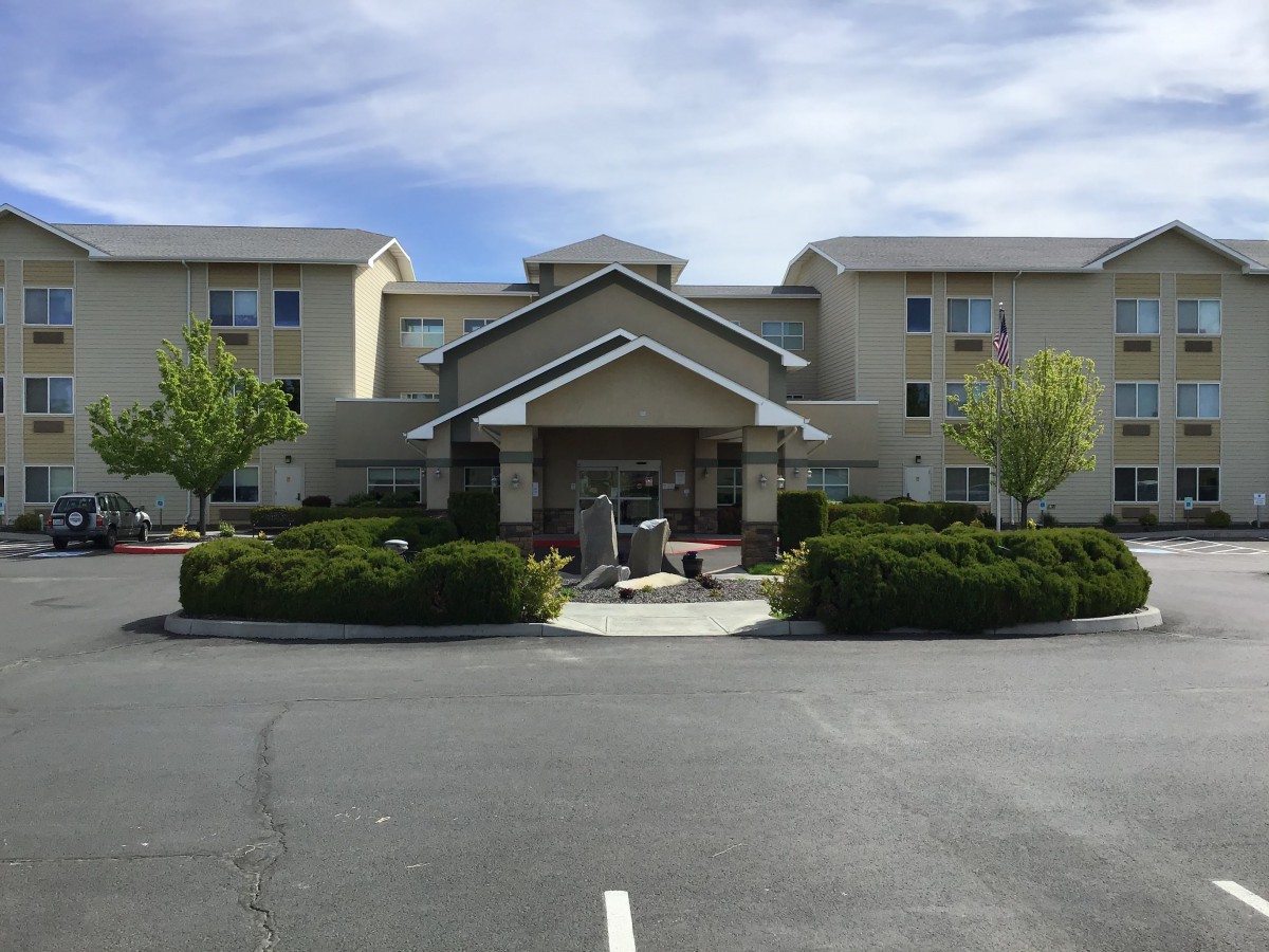 A view of the front entrance of a hotel with landscaped surroundings.