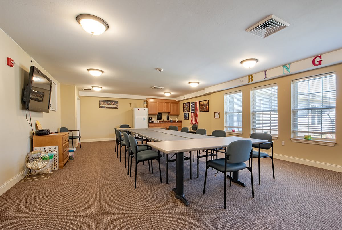 A spacious meeting room with a large conference table and chairs, adjacent to a small kitchen area.