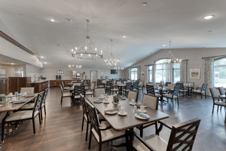 Spacious dining area with elegant chandeliers and neatly arranged tables and chairs.