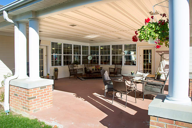 A cozy covered patio with outdoor furniture and hanging plants.