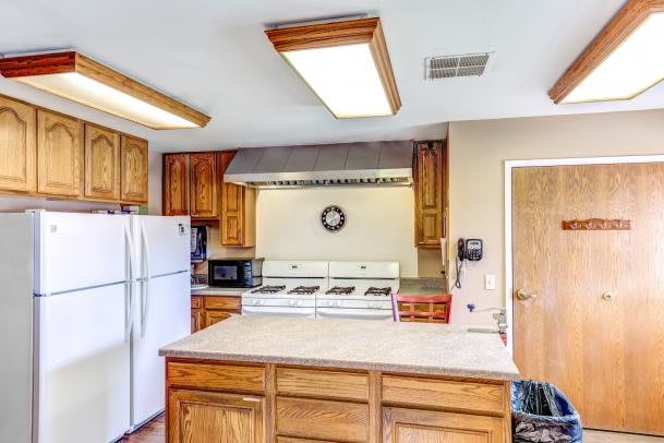 A spacious kitchen with wooden cabinets, a large refrigerator, and a central island.