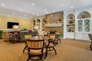 A cozy living room interior with a brick fireplace, surrounded by shelves and a seating area.