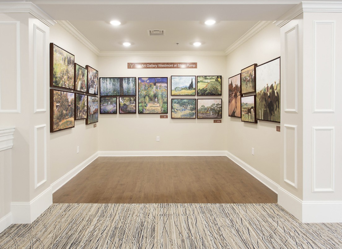 A well-lit art gallery showcasing a collection of framed paintings displayed on white walls.